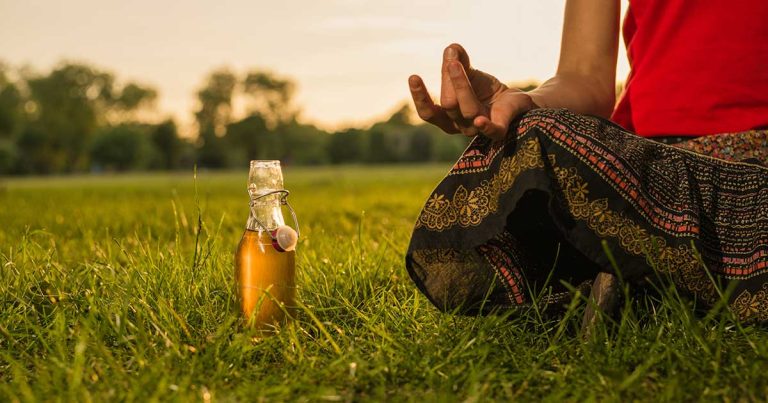 woman meditates with glass bottle