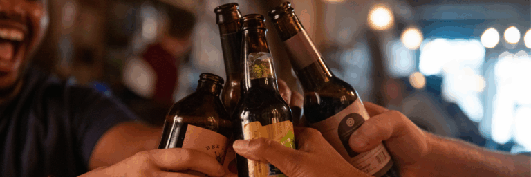 people toasting glass beer bottles